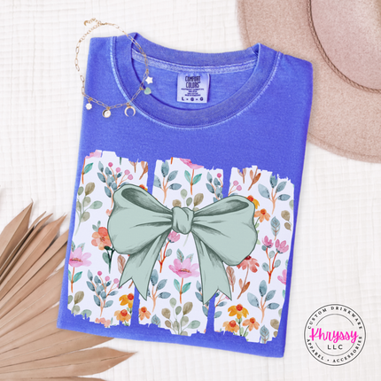 Fluorescent Blue tee with a sage green bow over watercolor wildflower panels