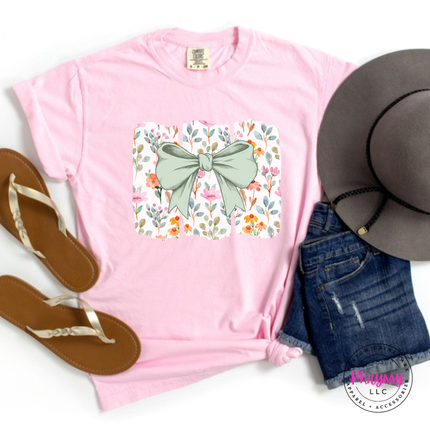 Blossom pink tee with a sage green bow over watercolor wildflower panels