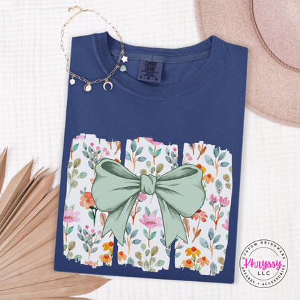 Navy tee with a sage green bow over watercolor wildflower panels