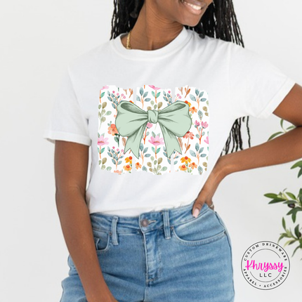 White tee with a sage green bow over watercolor wildflower panels