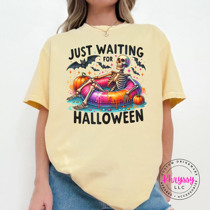 Butter tee showing a skeleton chilling on a pool float with pumpkins