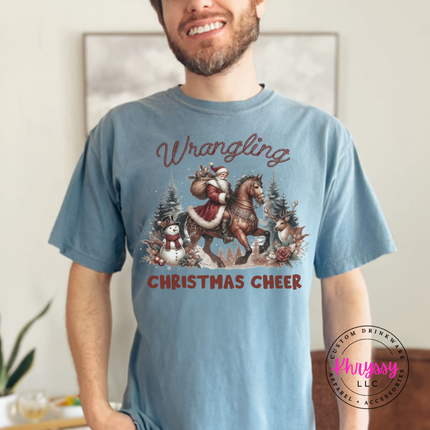 Wrangling Christmas Cheer tee in Ice Blue featuring Santa on horseback.