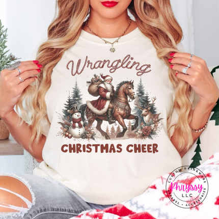 Wrangling Christmas Cheer tee in Ivory featuring Santa on horseback.