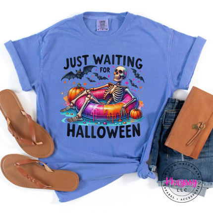 Flo Blue tee with a relaxing skeleton on a colorful pool float and bats