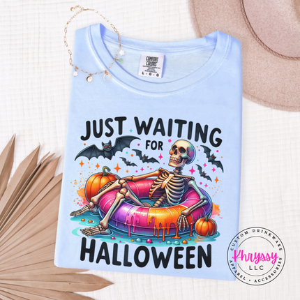 Hydrangea tee showing a skeleton on a pool float with Halloween pumpkins