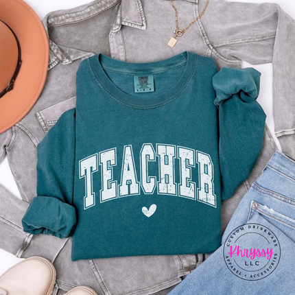 Flat lay of a Blue Spruce long sleeve tee with Teacher varsity lettering.