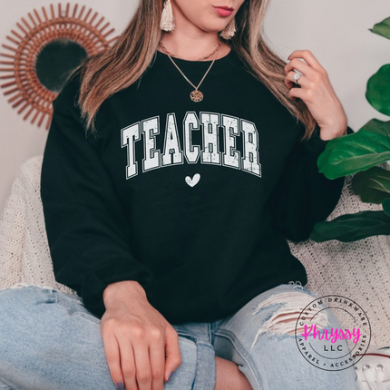 Woman wearing a Black crewneck sweatshirt with a distressed Teacher varsity arch.