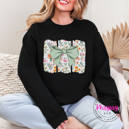 Black crewneck sweatshirt with a sage green bow over watercolor wildflower panels