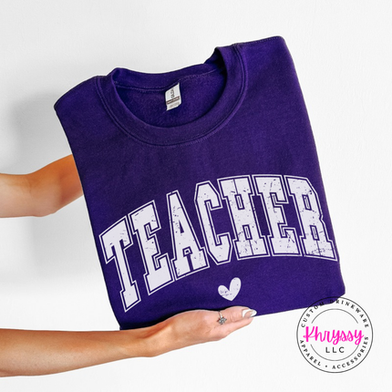 Folded Purple crewneck sweatshirt with a retro Teacher varsity arch print.