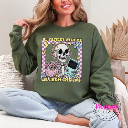 Military Green crewneck sweatshirt showing a laid-back skeleton in front of a striped retro sunset.