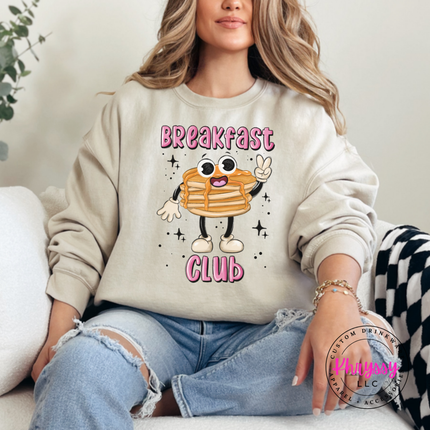 Sand crewneck sweatshirt showing a cartoon pancake stack under bold outlined Breakfast Club text.