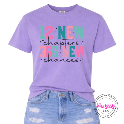 Violet tee showing colorful New Year lettering and black script.