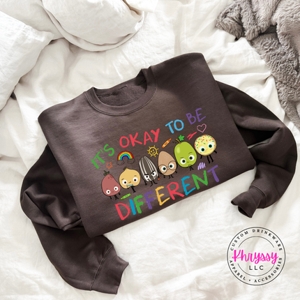 Bold colorful inclusion teacher crewneck on dark chocolate Gildan sweatshirt with vibrant rainbow character detail