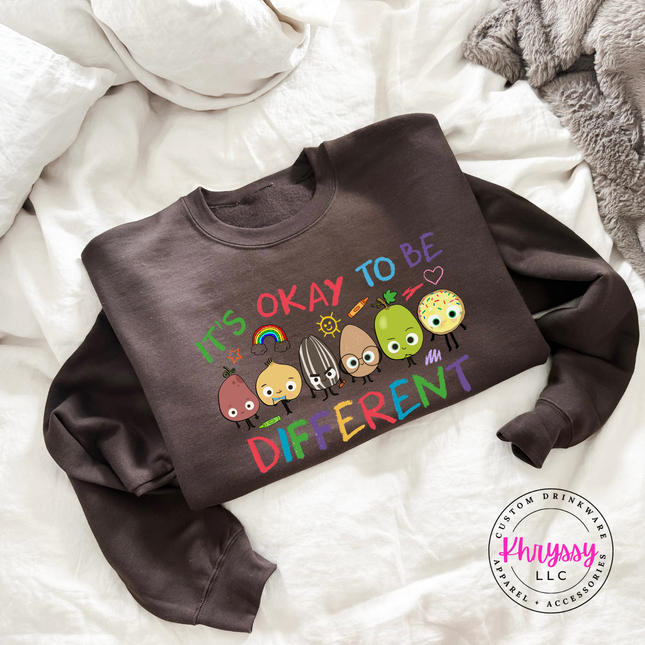 Bold colorful inclusion teacher crewneck on dark chocolate Gildan sweatshirt with vibrant rainbow character detail