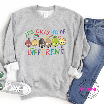 Warm neutral sport grey Gildan crewneck featuring bold colorful it’s okay to be different inclusion teacher graphic