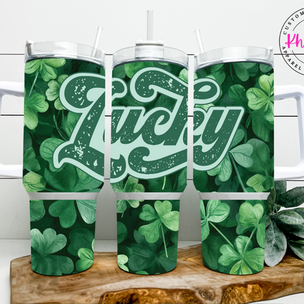 A 40oz stainless steel tumbler with a metal straw, featuring a green color scheme and the word 'LUCKY' in a bold, white font surrounded by shamrocks.