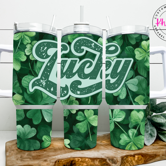 A 40oz stainless steel tumbler with a metal straw, featuring a green color scheme and the word 'LUCKY' in a bold, white font surrounded by shamrocks.