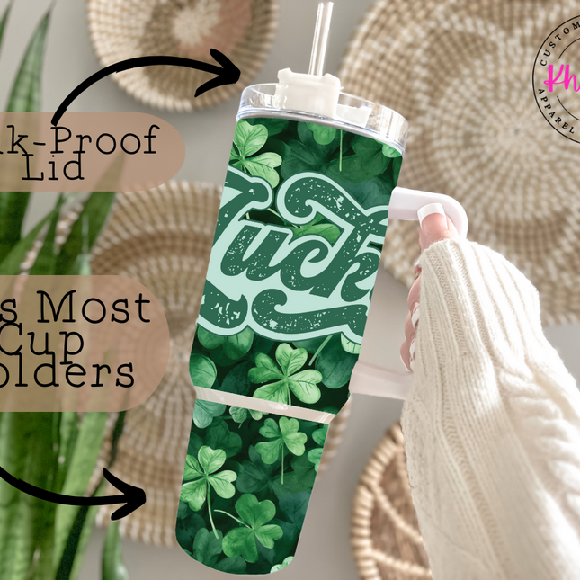 A 40oz stainless steel tumbler with a metal straw, decorated in a vibrant green theme and displaying the word 'LUCKY' in large, white lettering. The design is accented with small shamrocks scattered around the text.
