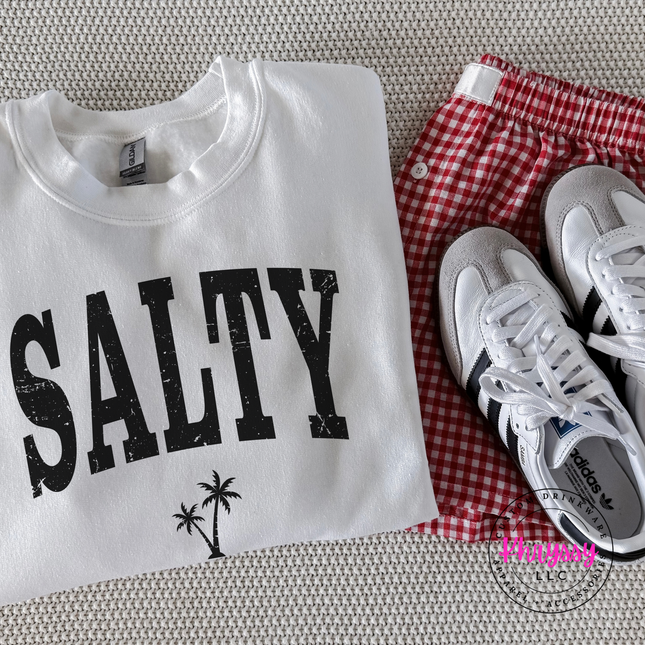 White crewneck sweatshirt displaying a black distressed SALTY beach graphic.