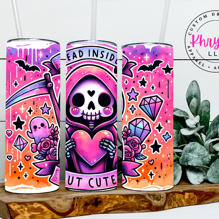 Colorful tumbler with decorative designs on a wooden surface with a plant in the background.