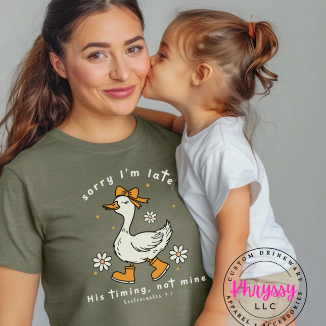 Woman wearing a green t-shirt with a duck graphic and text, child kissing her on the cheek.