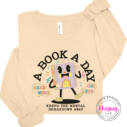 Soft Cream Bella Canvas long sleeve with the warm retro cartoon book character A Book A Day print.