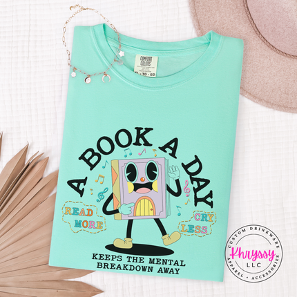 Island Reef soft cotton tee featuring the pastel lavender book character and A Book A Day lettering.