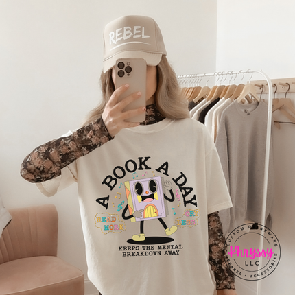 Ivory Comfort Colors tee printed with the retro cartoon A Book A Day Keeps The Mental Breakdown Away graphic.