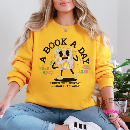 Gold pullover hoodie featuring the pastel lavender book character and A Book A Day lettering.