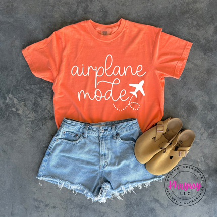 Melon garment-dyed tee with a black airplane mode travel graphic across the chest.