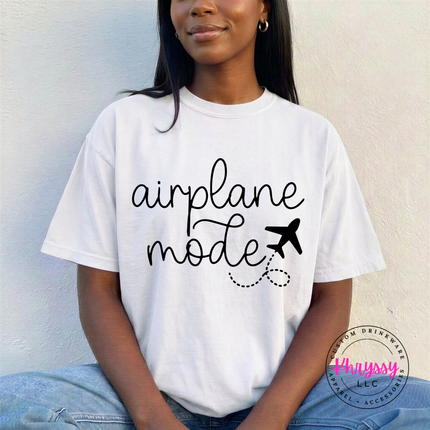 White garment-dyed tee displaying a black airplane mode script and plane graphic.