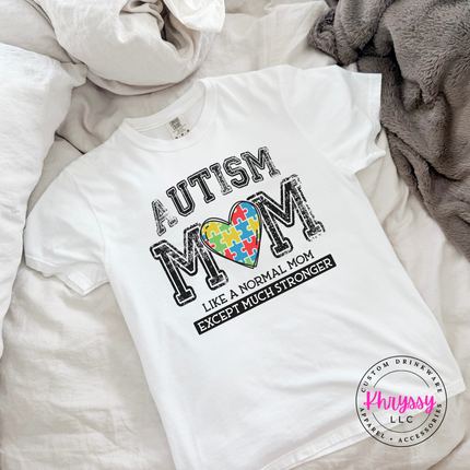 Close-up of a rainbow puzzle-piece heart graphic on a White cotton tee.