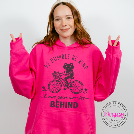 Woman wearing a Heliconia hoodie with the black be humble be kind frog