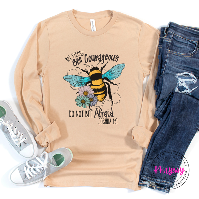 Sand long-sleeve shirt with bee graphic and text, paired with jeans and sneakers on a white background.