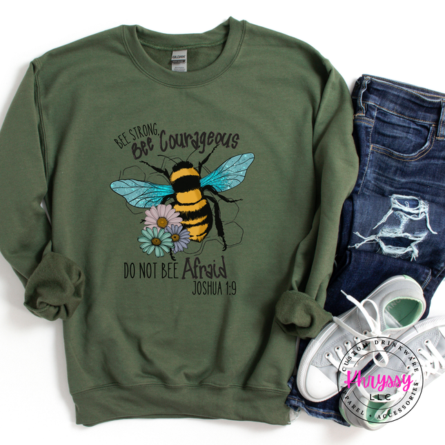 Green sweatshirt with bee design and text, paired with jeans and sneakers on a white background.