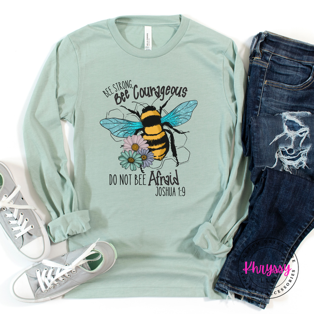 Mint green long-sleeve shirt with bee graphic and text, paired with jeans and sneakers on a white background.