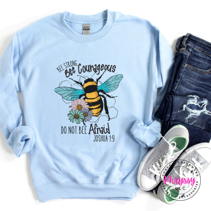 Light blue sweatshirt with bee graphic and text, paired with jeans and sneakers on a white background.