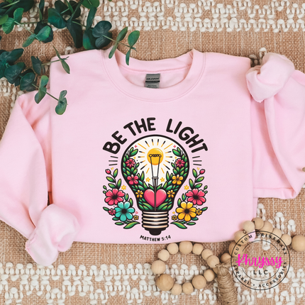 Light Pink crewneck sweatshirt showing a blooming lightbulb and Matthew verse