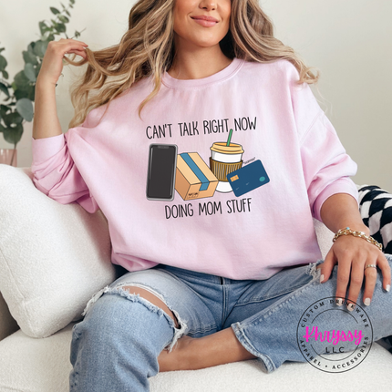 Woman wearing a Light Pink crewneck sweatshirt with the doing mom stuff graphic