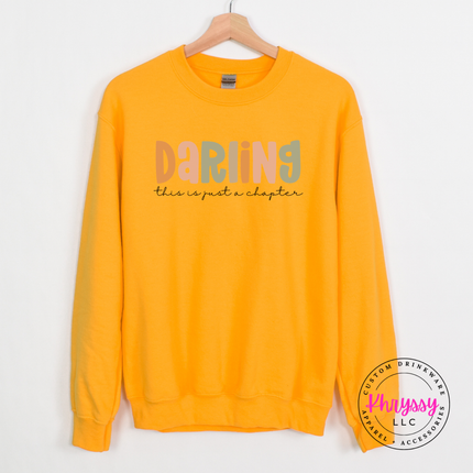 Gold crewneck sweatshirt featuring a just-a-chapter script reminder