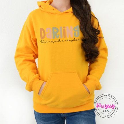 Gold hoodie featuring a just-a-chapter script reminder in soft colors