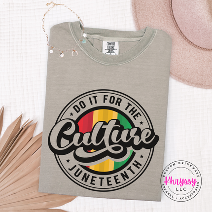 Sandstone tee with a black Juneteenth badge and red gold green center.
