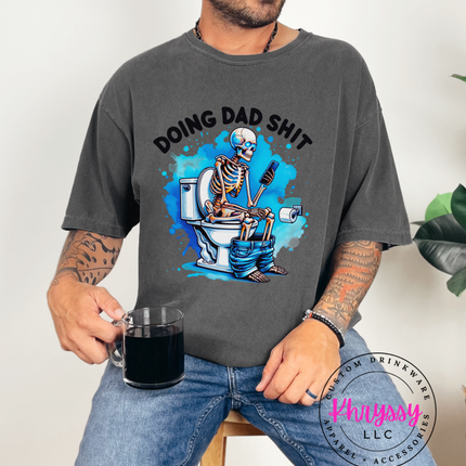 Man wearing a gray t-shirt with a skeleton graphic and text, holding a mug.