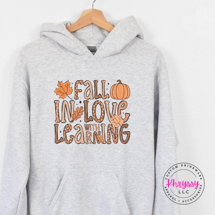 Woman wearing an Ash pullover hoodie with a Fall In Love design.