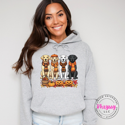 Woman wearing an Ash heavyweight hoodie with a fall labrador puppies graphic.