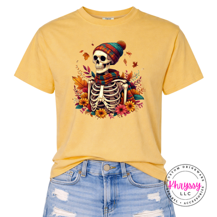 Mustard graphic tee featuring a cozy skeleton in a plaid scarf and beanie.