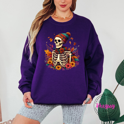 Purple crewneck sweatshirt with the spooky cozy skeleton fall graphic