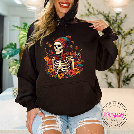 Woman wearing a Dark Chocolate pullover hoodie with a fall skeleton design.