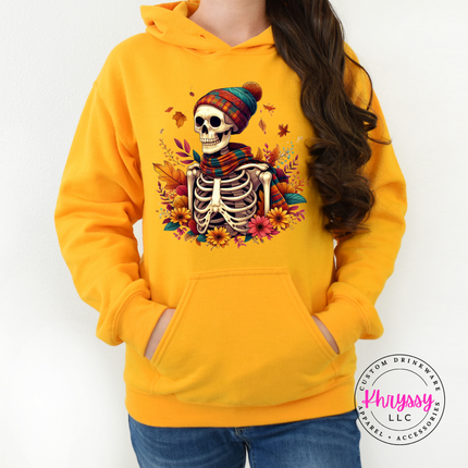 Gold colored hoodie featuring a cozy skeleton in a plaid beanie.