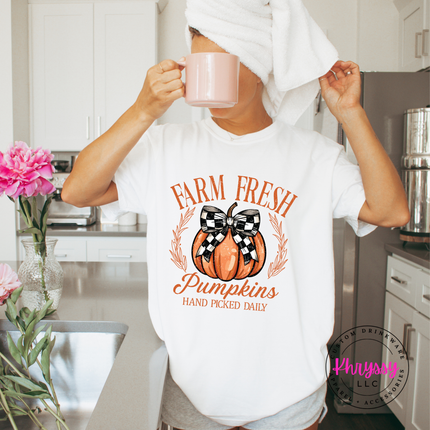 Woman wearing a white colored tee with a farm fresh pumpkin design.